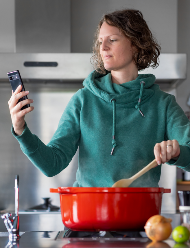 Une utilisatrice suit un guide Doozis sur son téléphone en cuisinant